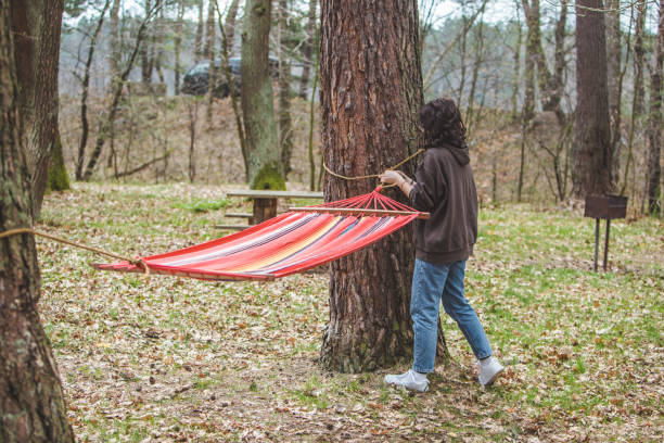 woman ties up hammock in forest woman ties up hammock in forest between trees women lying down grass wood stock pictures, royalty-free photos & images