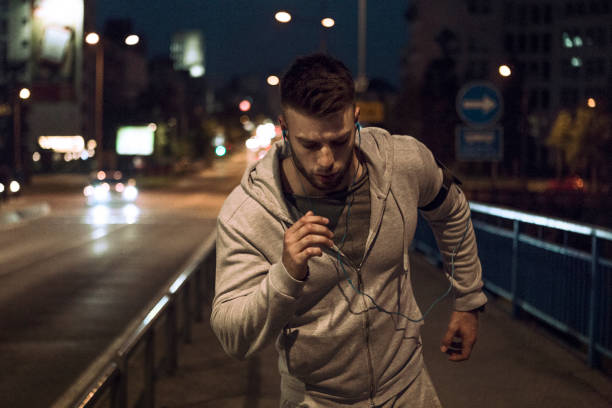 istock Young man with jogging through the city at night 1170832623