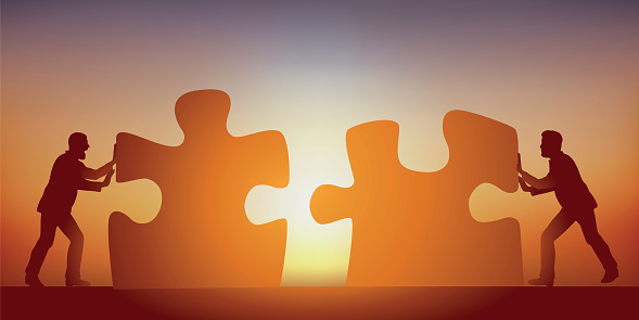 Concept of partnership to find a solution to a problem, with two men pooling their intelligences, symbolized by two puzzle pieces.