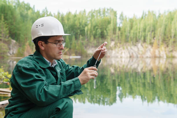 ecologista industriale prende un campione d'acqua dal lago nel sito di una cava allagata - impurities foto e immagini stock