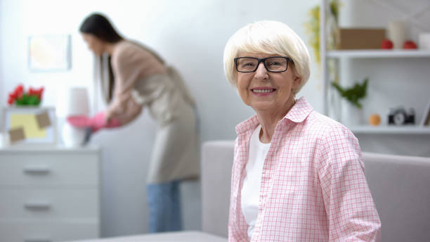 donna anziana sorridente che guarda la macchina fotografica, governante che pulisce la polvere in camera, pulizia - grandparent adult smiling looking at camera foto e immagini stock