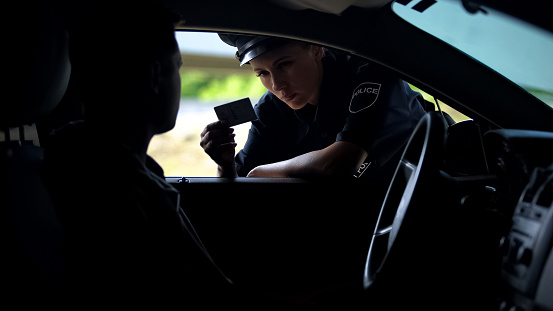 Mujer policía verificando documentos de conductor, inspección en carretera, infracción de tráfico photo