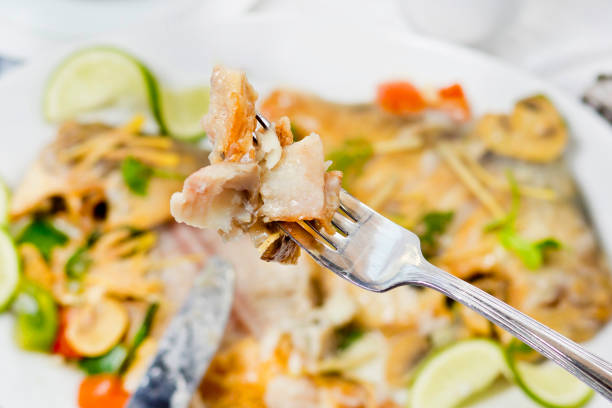 Pieces of Pomfret fish on a fork close-up.