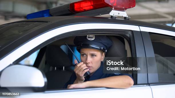 Police Woman In Car Taking On Portable Radio Informing During Area Patrolling Stock Photo - Download Image Now