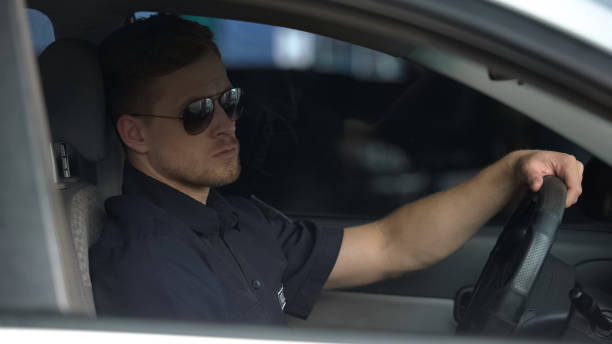 istock Confident policeman sitting in patrol car and wearing sunglasses, ready for work 1170855596