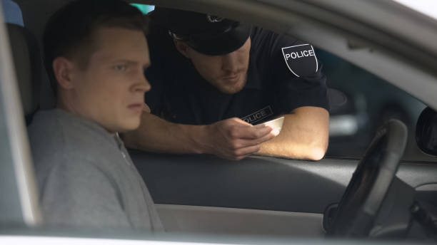istock Police officer checking documents of nervous man in car, traffic control, rules 1170855657