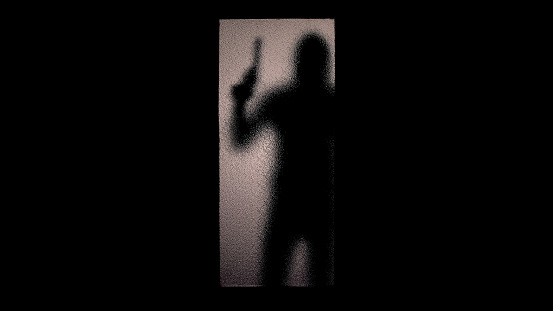 Silhouette of hooded criminal holding gun at glass door, contract killing crime