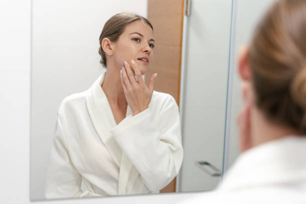 istock Woman in bathrobe looking in mirror at bathroom 1170856370