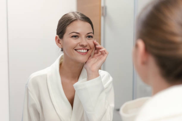 istock Woman in bathrobe looking in mirror at bathroom 1170856523