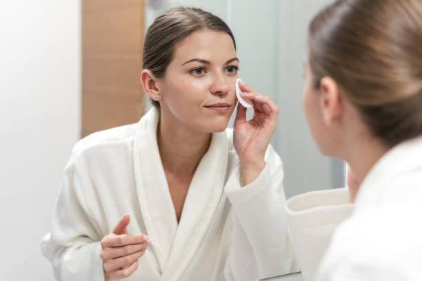 Woman in white bathrobe holding cotton pad in hands