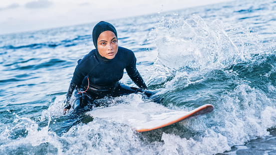 Female surfer with hijab in sea