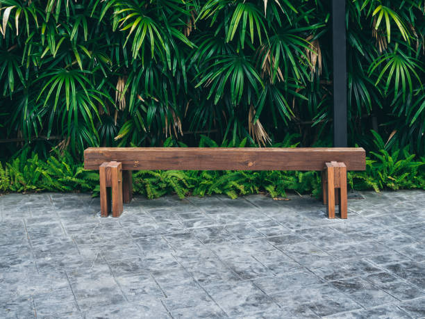 istock Rustic solid railway sleeper wooden bench on concrete floor with modern hand woven bamboo light on tropical green bush and bamboo wall background. 1170867616