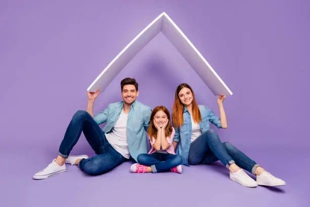 Photo of Family portrait of three members sitting floor under new roof wear casual clothes isolated purple background