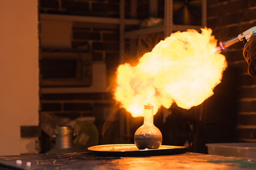 Lab technician setting fire to a ball with hydrogen blowtorch