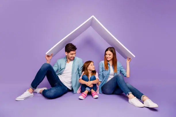 Photo of Family portrait of three members sitting floor under new roof wear casual clothes isolated purple background