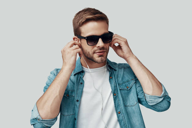 istock Handsome young man listening music while standing against grey background 1170873668