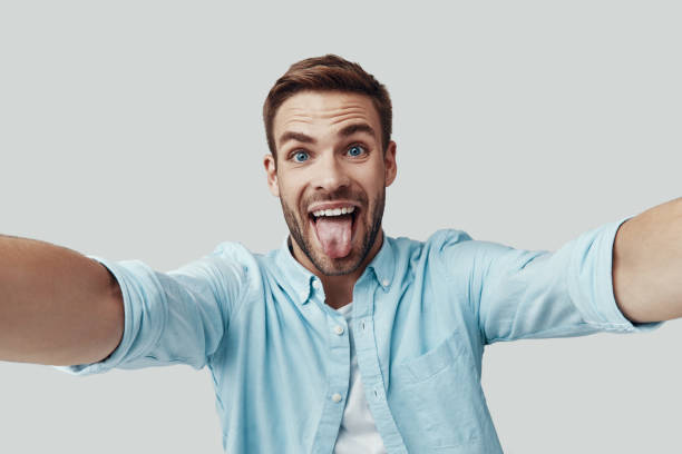 istock Self portrait of handsome young man looking at camera and smiling while standing against grey background 1170874909