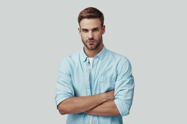 istock Handsome young man looking at camera and keeping arms crossed while standing against grey background 1170875743