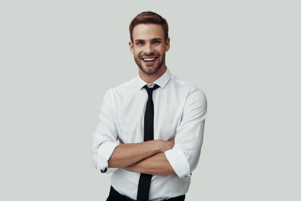 istock Handsome young man in formalwear looking at camera and smiling while standing against grey background 1170876037