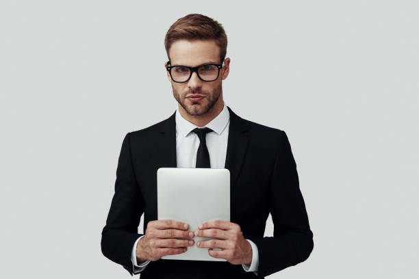 istock Handsome young man in formalwear looking at camera while standing against grey background 1170877679