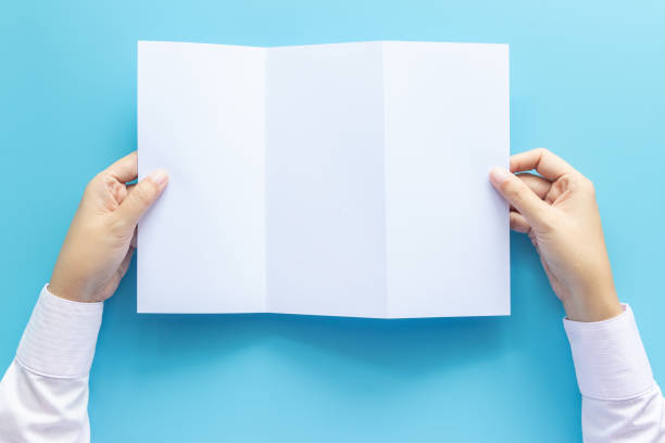 istock hand holding blank white paper for letter mock up, isolated on blue background with copy space. studio shot, horizontal 1170877763