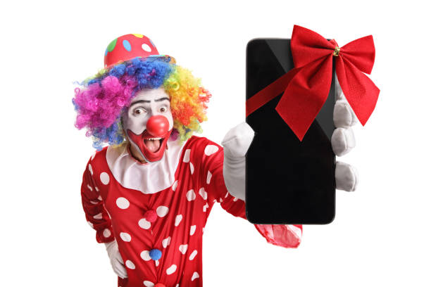 palhaço feliz que mostra um smartphone com um laço vermelho - clown circus telephone humor - fotografias e filmes do acervo