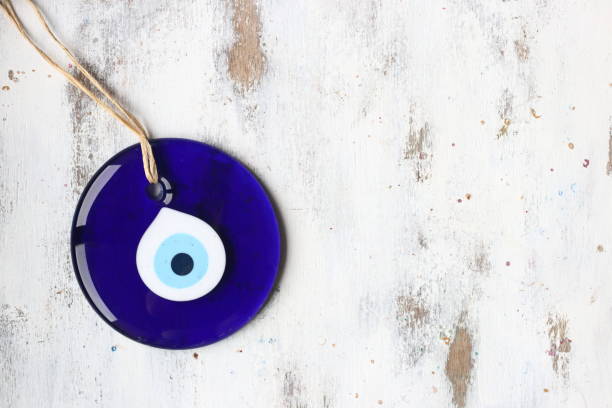 evil eye bead, turkish nazar bead on a white wooden background - evil eye beads imagens e fotografias de stock