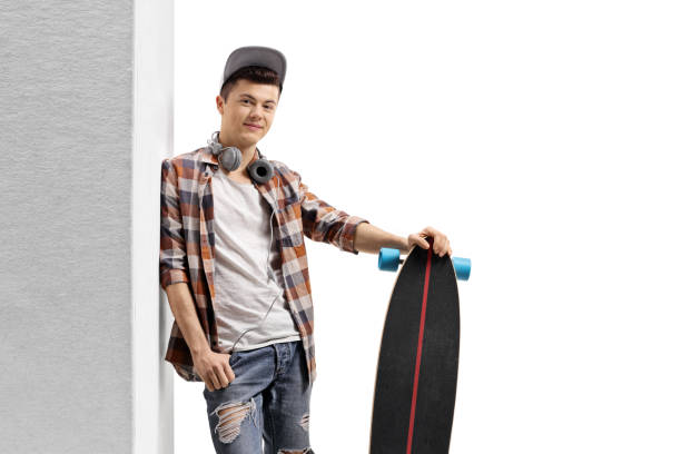 istock Young boy hipster with a longboard leaning against wall 1170891192