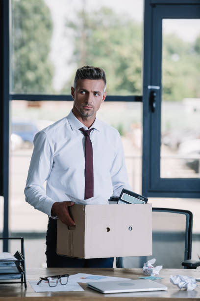 istock serious businessman holding box while standing near workplace 1170894570