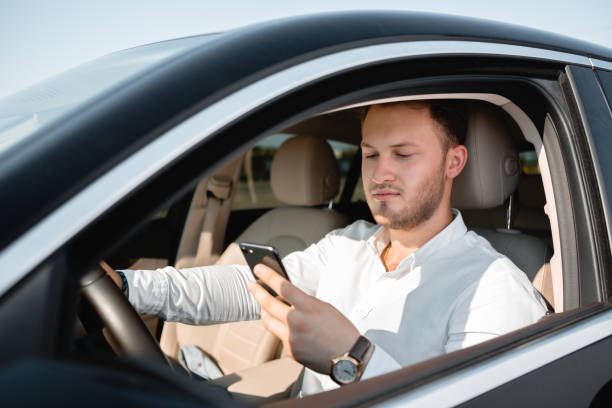 istock Young businessman smiling looking at mobile phone while driving a car. 1170895160