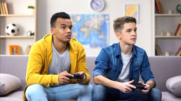 amigos afro-americanos e caucasianos do adolescente que jogam o jogo video - threats men african descent caucasian - fotografias e filmes do acervo