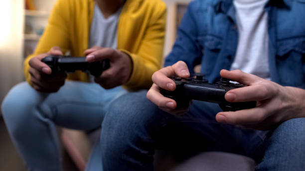 istock Multiracial friends playing computer games, closeup on hands with joysticks 1170896178