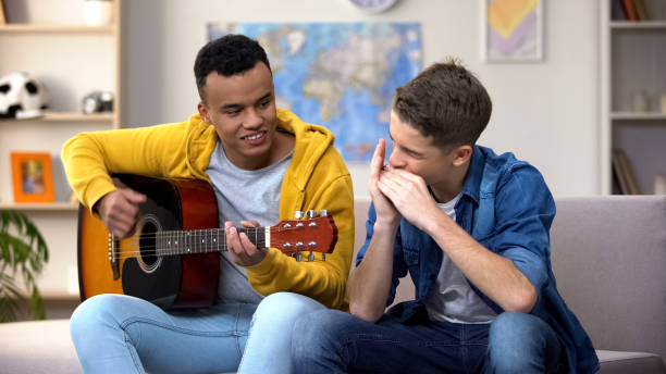 multiracial teenage friends playing guitar and mouthorgan hobby musician career - singing singer teenager contest imagens e fotografias de stock