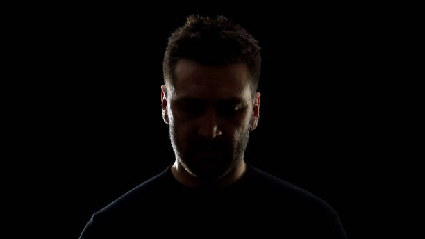 istock Sad male in shadow looking down feeling ashamed, problem frustration, regret 1170896565