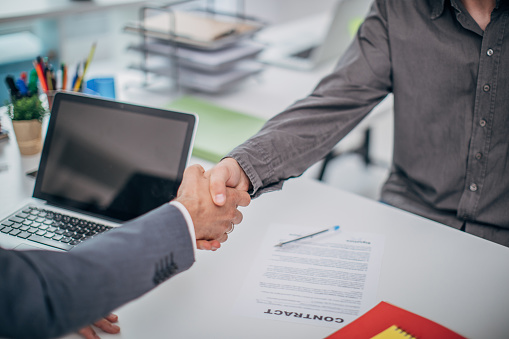 Two businessmen handshaking in the office after they signed the contract