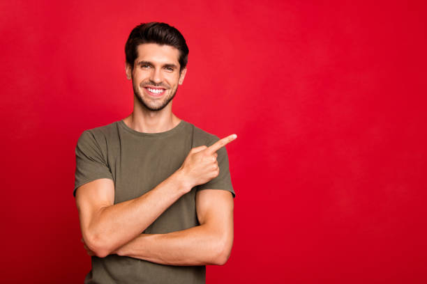 istock Macho guy indicating finger empty space on low shopping spices wear grey t-shirt isolated on red background 1170897662
