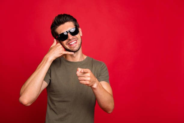 Cool guy speaking over imaginary, telephone advertising operator service wear grey t-shirt isolated on red background