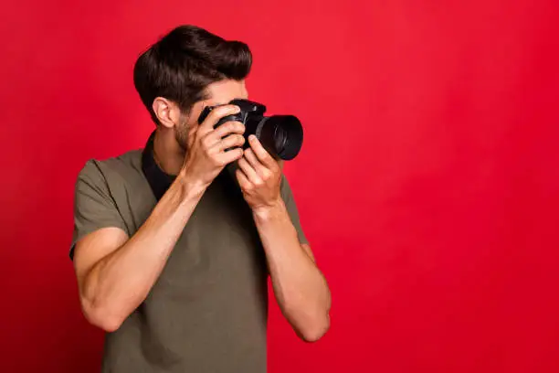 Photo of Amazing guy with photo digicam making pictures wear casual grey t-shirt isolated on red background