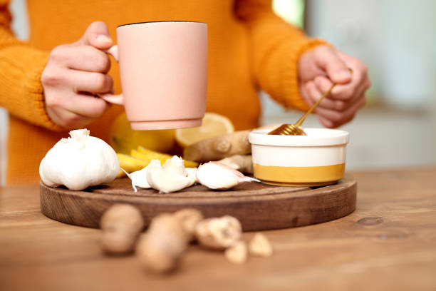Woman’s hand holding mug of warming tea with honey stock photo