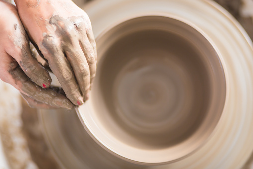 Close up of female hands working on potters wheel