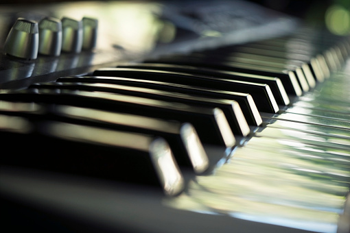 Electric piano keyboard in blur. Piano keyboard with day light reflections.