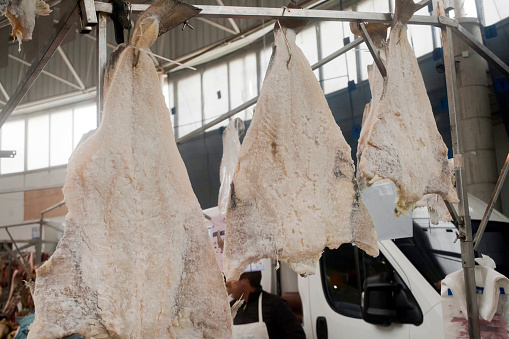 Three pieces of salted dried cod fish hanging, retail display in a market stall.Traditional festival, Monterroso, Lugo province, Galicia, Spain. Traditional Christmas food.