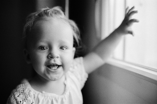 Black and white indoor portrait of smiling baby girl of one year old. Retro style shot