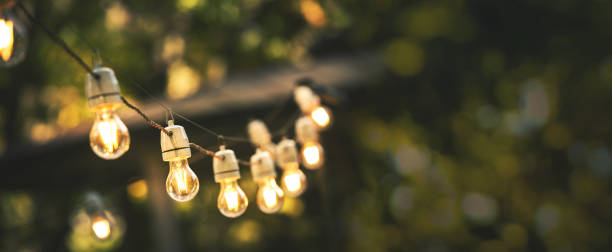 luci stringa festa all'aperto appese nel cortile di casa su sfondo bokeh verde con spazio copia - patio foto e immagini stock