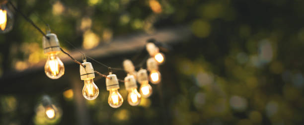 outdoor party string lights hanging in backyard on green bokeh background with copy space outdoor party string lights hanging in backyard on green bokeh background with copy space light strings stock pictures, royalty-free photos & images