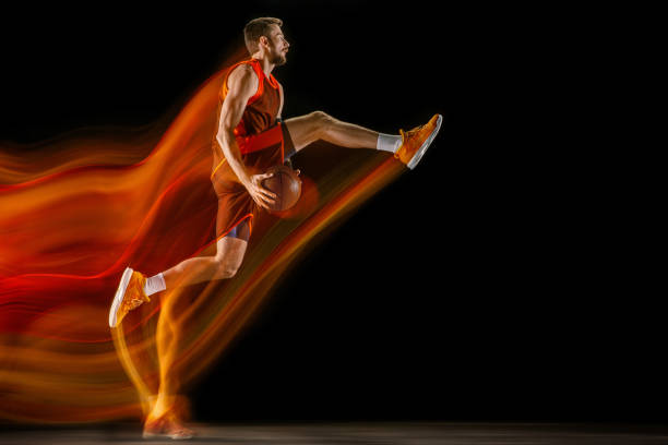 istock Young caucasian basketball player against dark background in mixed light 1170916436