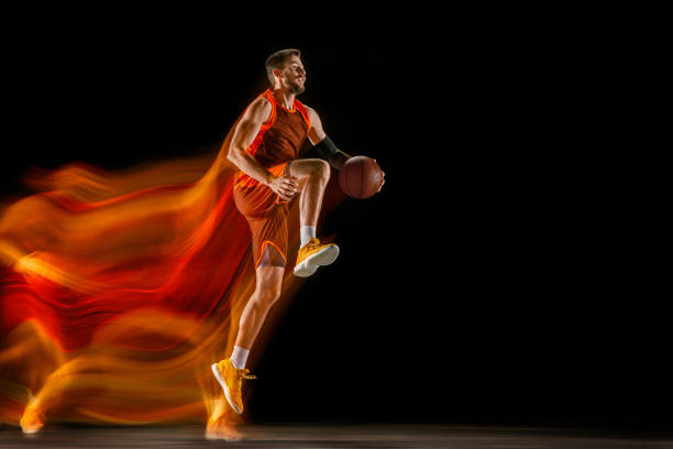 istock Young caucasian basketball player against dark background in mixed light 1170916441