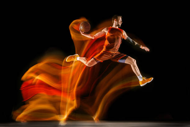 istock Young caucasian basketball player against dark background in mixed light 1170916442