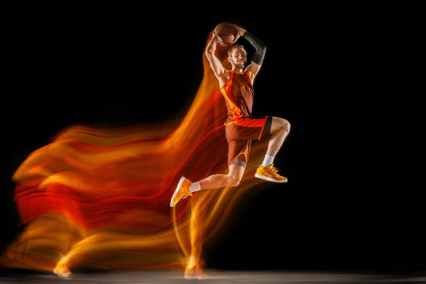 istock Young caucasian basketball player against dark background in mixed light 1170916453