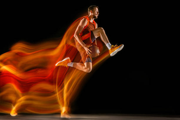 istock Young caucasian basketball player against dark background in mixed light 1170916462